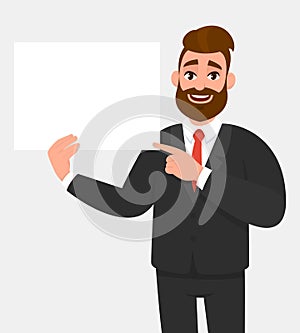 Hipster young businessman showing blank white poster and pointing finger. Happy trendy person holding empty banner.