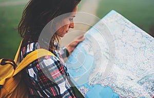 Hipster young girl with backpack holding in hands and looking on map spain of foggy mountain, tourist traveler hiker on background