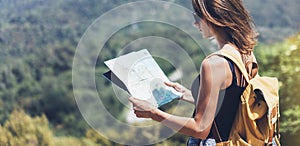 Hipster young girl with bright backpack enjoying panoramic mountain sea, using map and looking distance. Tourist traveler on back