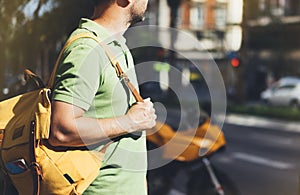 Hipster young man holding in hands backpack and map. Side view tourist traveler planning route on background sun and orange moto