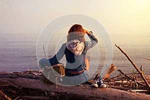 Hipster young tourist girl in jeans, sneakers with a bag sitting