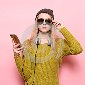 Hipster young woman using cell phone and selecting music to listen on headphones.