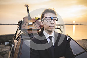 Hipter in glasses and his guitar on car rack