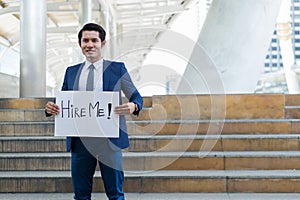 Hire me! Handsome businessman wear blue suit holding poster with hire me text message