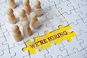 We are hiring text on missing jigsaw puzzle with wooden dolls.. Hiring and employment concept