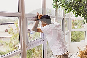 His 53-year-old Asian senior man stood nervously, looking out the window.