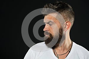 His beard is styled appropriately. Brutal hipster with textured beard hair on black background. Bearded man with stylish