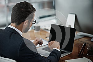 His business has gone global. a young businessman making a video call on a laptop in an office.