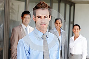 His colleagues respect him. A young business leader standing in front of his team confidently.