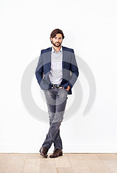 His confidence knows no bounds. Portrait of a confident young businessman leaning against a white wall.