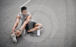 His determination is unfaltering. a sporty young man stretching his legs while exercising outdoors.