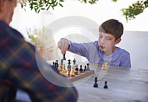 His granddad is a worthy adversary. Shot of a young boy playing chess with his grandfather.