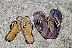 His and hers flip flop sandals on the sandy beach