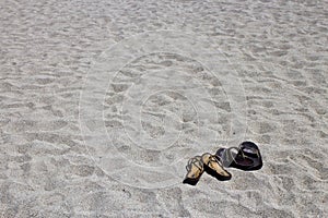 His and hers flip flop sandals on the sandy beach