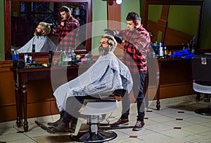 In his own style. handsome hairdresser cutting hair of male client. Hairstylist serving client at barber shop. Personal