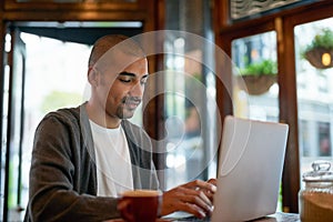 This is his perfect working environment to stay productive. a young man working on his laptop in a cafe.