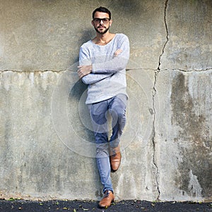 His style game is strong. Shot of a handsome young man posing against an urban wall.