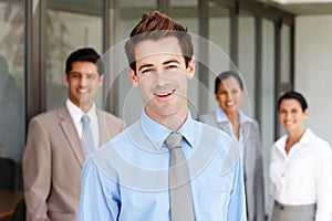 His team management is exemplary. A young business leader standing in front of his team smiling confidently.