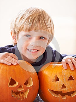 His very own jack-o-lanterns. Portrait of a young boy behind a two jack-o-lanterns.