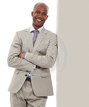 On his way to the top. A handsome African-American businessman leaning against a wall.