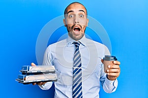 Hispanic adult business man holding take away coffee and sweets afraid and shocked with surprise and amazed expression, fear and