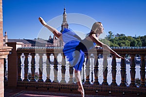 Hispanic adult female classical ballet dancer in blue tutu doing figures on the terrace of a plaza next to a beautiful tiled