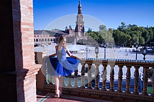 Hispanic adult female classical ballet dancer in blue tutu doing figures on the terrace of a plaza next to a beautiful tiled