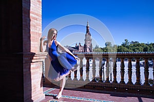 Hispanic adult female classical ballet dancer in blue tutu doing figures on the terrace of a plaza next to a beautiful tiled