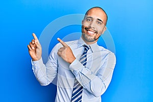 Hispanic adult man wearing business shirt and tie smiling and looking at the camera pointing with two hands and fingers to the