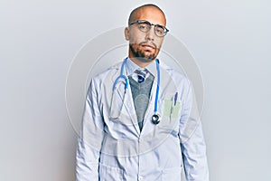 Hispanic adult man wearing doctor uniform and stethoscope looking sleepy and tired, exhausted for fatigue and hangover, lazy eyes