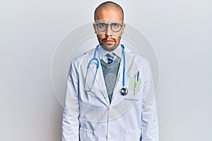 Hispanic adult man wearing doctor uniform and stethoscope skeptic and nervous, frowning upset because of problem