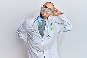 Hispanic adult man wearing doctor uniform and stethoscope suffering of neck ache injury, touching neck with hand, muscular pain