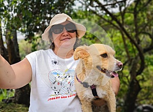 Hispanic adult woman enjoying nature with her pet, a small yellow dog