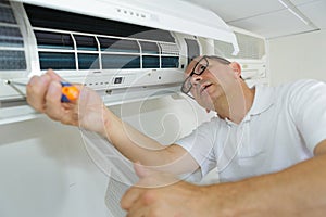 Hispanic airconditioning repair man performing maintenance