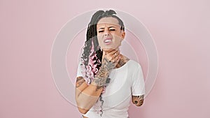 Hispanic amputee woman stands over isolated pink background, gripping painful neck in the throes of flu and painful throat