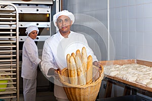 Hispanic baker showing fresh baked baguettes in bakery