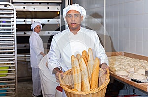 Hispanic baker showing fresh baked baguettes in bakery