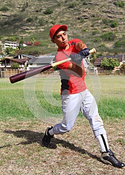 Hispanic baseball player mid-swing