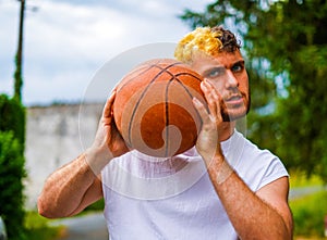 Hispanic basketball player posing with a basket ball