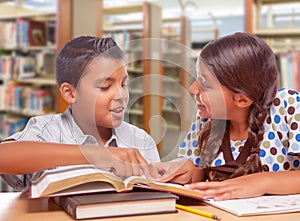 Hispanic Boy and Girl Having Fun Studying Together In The Library