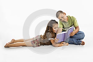 Hispanic boy and girl reading book together.