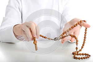 A Hispanic boy is holding Rosary beads with both hands