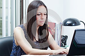 Hispanic brunette office woman sitting by desk and