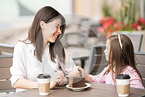 Hispanic brunette talking with a little girl in a cafe