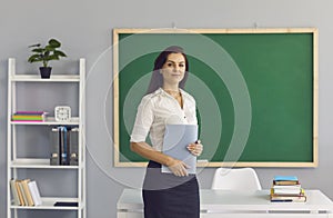 Hispanic brunette teacher with a book in his hand standing in class.