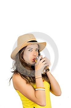 Hispanic brunette wearing yellow football shirt and hat, posing for camera while drinking from beer glass, white studio