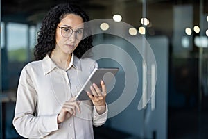 Hispanic business woman using a tablet in modern office