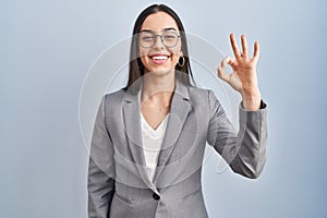 Hispanic business woman wearing glasses smiling positive doing ok sign with hand and fingers