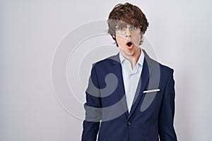 Hispanic business young man wearing glasses afraid and shocked with surprise and amazed expression, fear and excited face