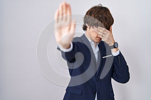 Hispanic business young man wearing glasses covering eyes with hands and doing stop gesture with sad and fear expression